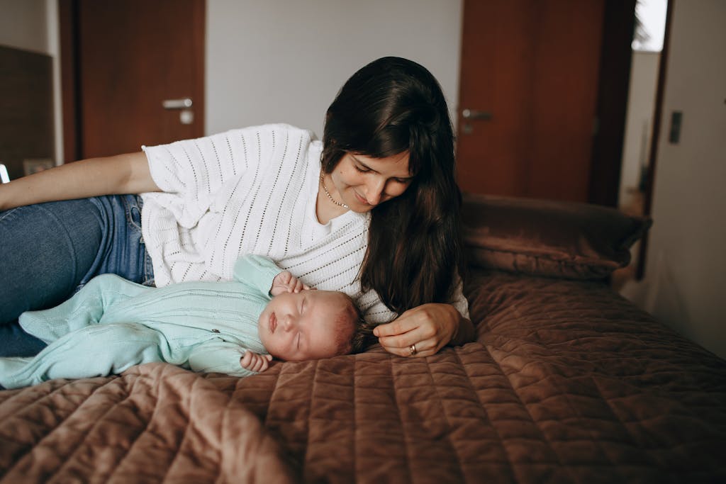 A woman and baby laying on a bed