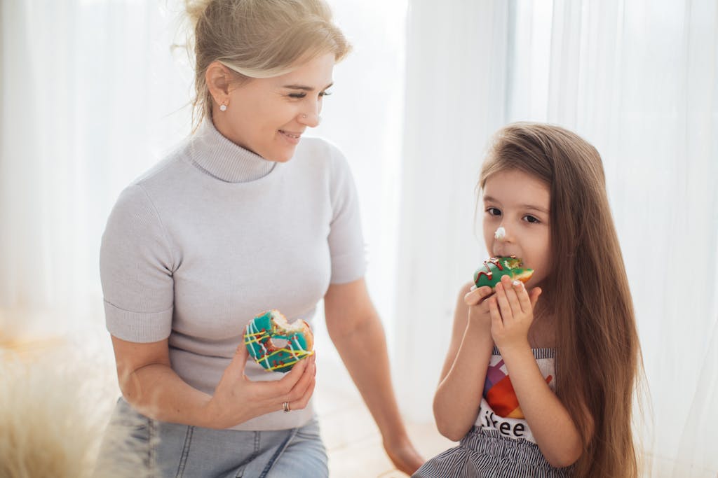 Photo of a Child and a Woman Eating Donuts Together