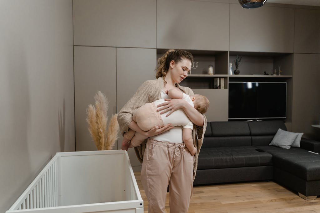 Woman in Brown Pants Carrying Baby in White Onesie