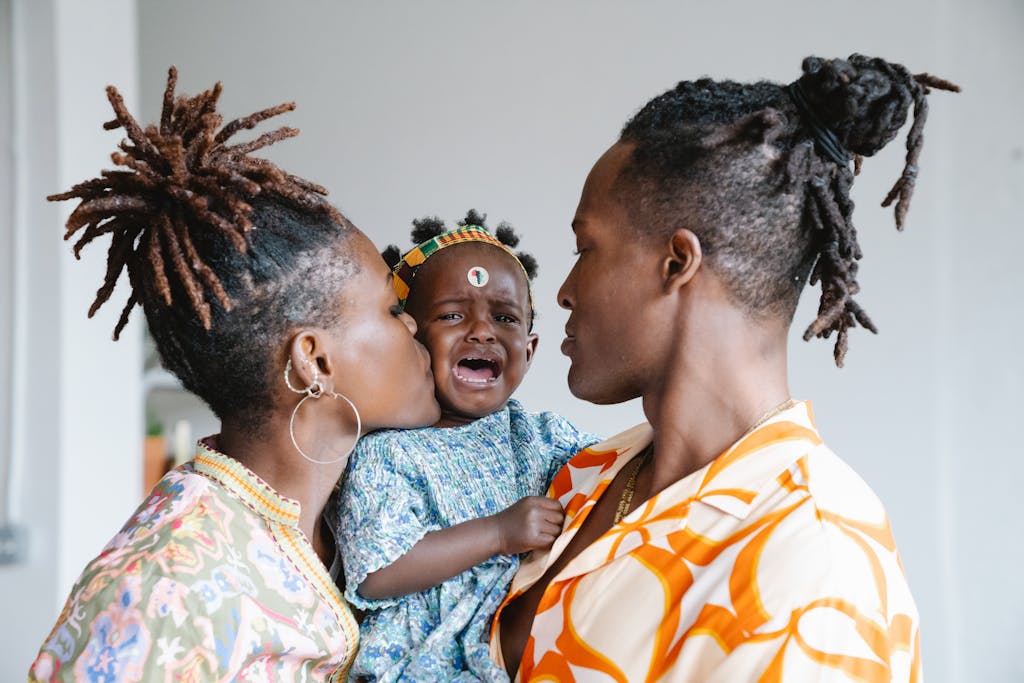 A touching family moment with parents comforting their crying child indoors.